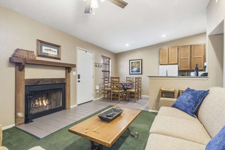 Living Room With Fireplace, Furnished Seating, Kitchen Counter, And Ceiling Fan