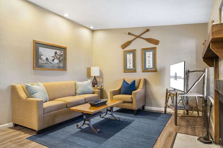 Living Room With Light Walls And Blue Rug, Featuring A Couch, Chair, And TV Living Room With Light Walls And Blue Rug, Featuring A Couch, Chair, And TV