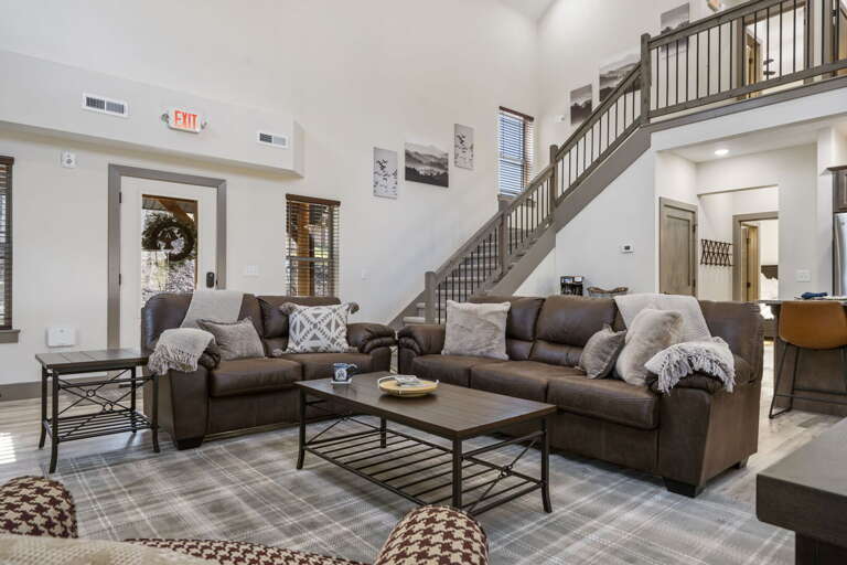 Spacious Living Room With Stairs, Sofas, And Checkered Rug In A Vacation Rental