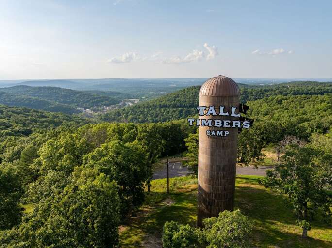 Aerial View Of Tall Tower With Tall Timbers Camp Sign Surrounded By Verdant Vegetation