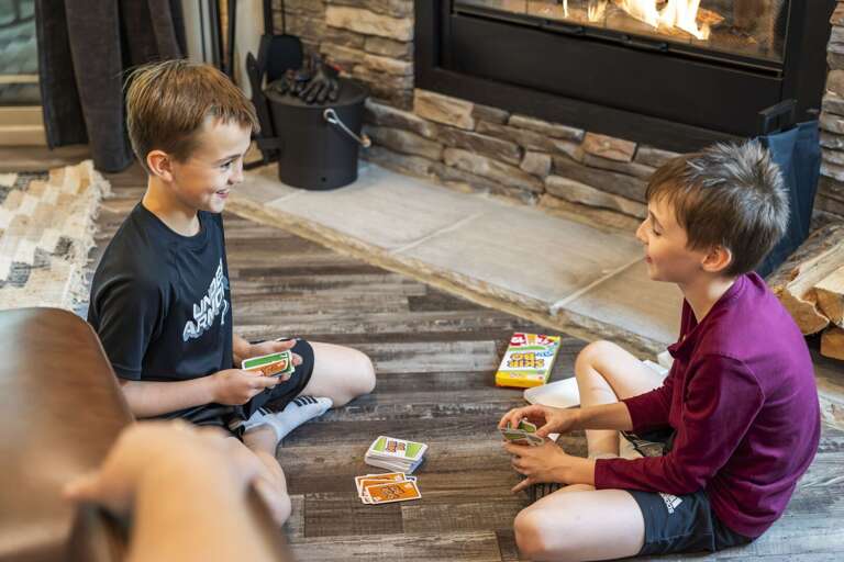 Boys Playing Card Game By Blazing Fireplace