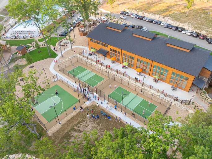Aerial View Of Large Building With Adjacent Parking And People Playing Pickleball
