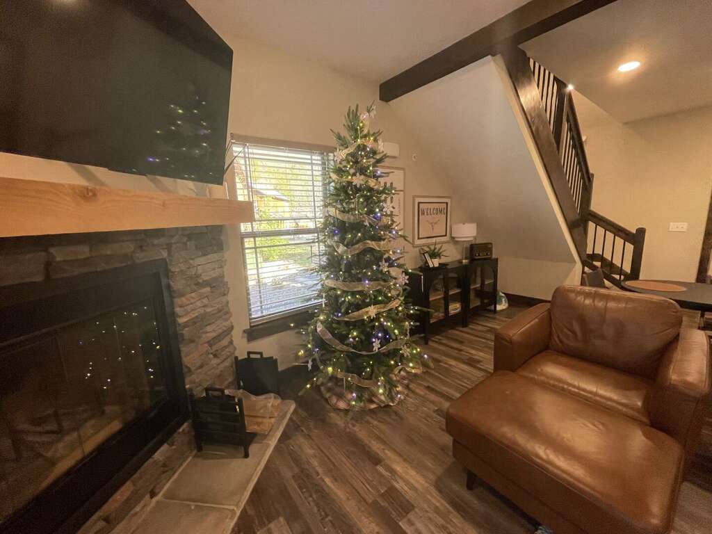 Interior Showing A Christmas Tree Beside A Staircase, Leather Sofa, And A Fireplace