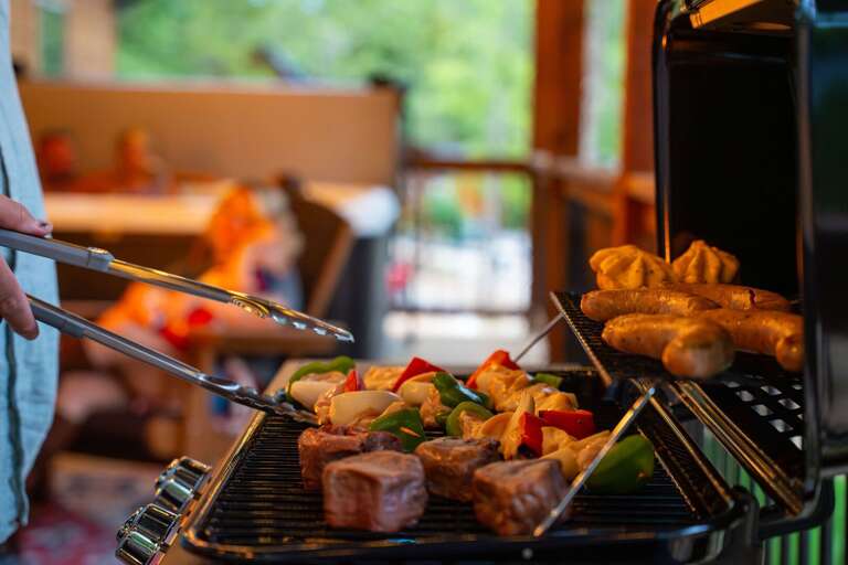 Person Preparing Food On Grill At Vacation Rental