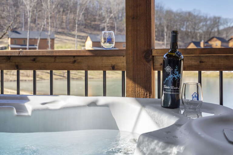 Bottle Beside Bubbly Bath, Backdrop Of Bare Branches And Buildings