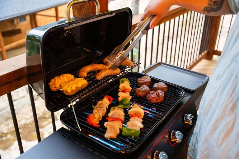 Person Preparing Food On Portable Grill On Balcony