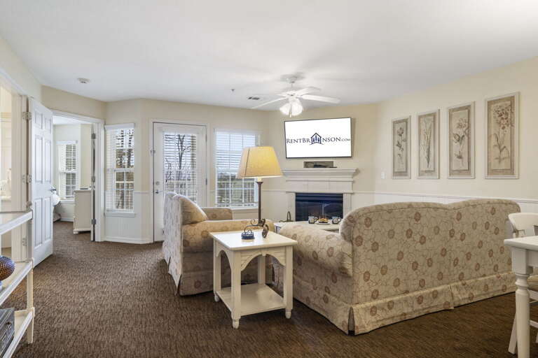 Brightly Lit Living Space With Beige Sofas, A Fireplace, And French Doors