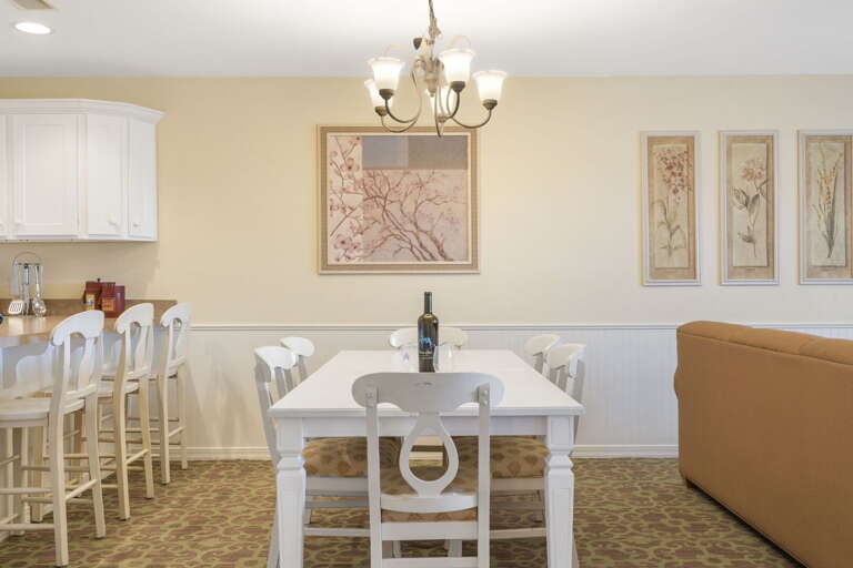 Spacious Dining Space With White Tables And Beige Walls, Adorned With Framed Art