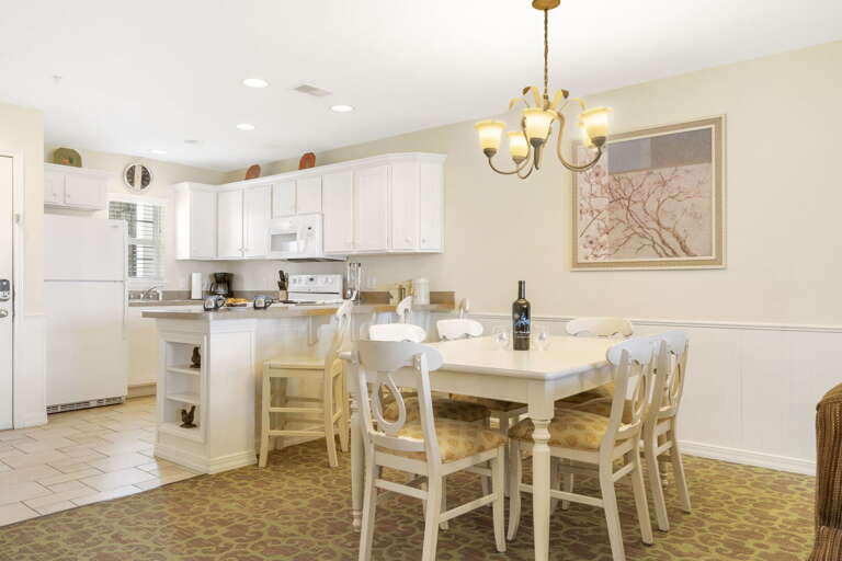 Spacious Kitchen And Dining Area In Vacation Rental With White Cabinets And Table Set