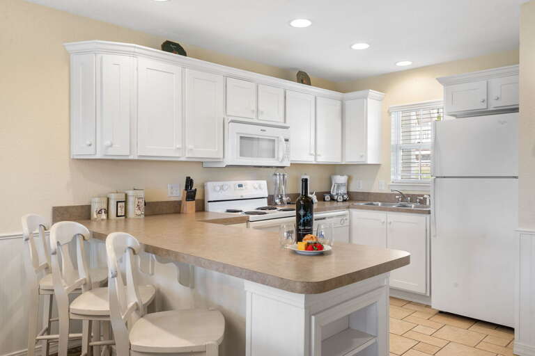 Bright Kitchen In Vacation Rental With White Cabinets And Breakfast Bar