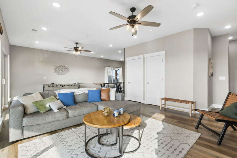 Spacious Living Space With Sofas, Round Coffee Table, Ceiling Fans, Leading To Kitchen Area