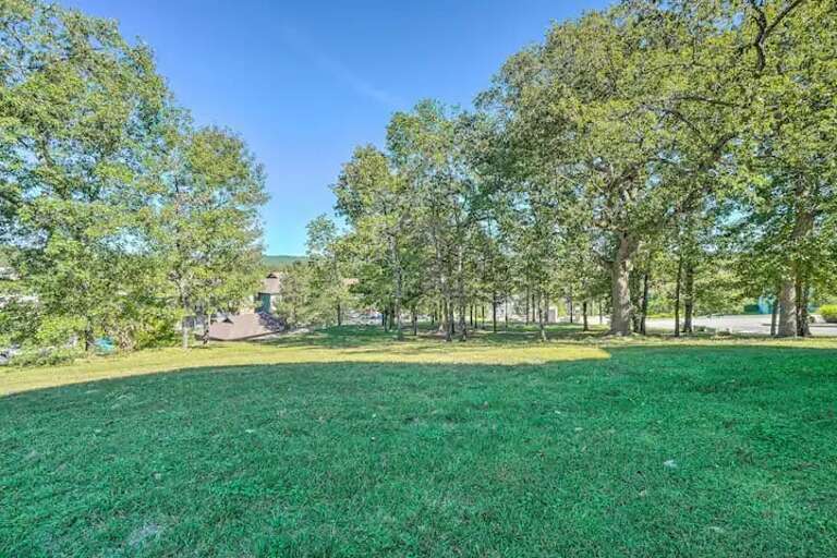 Green Grass And Leafy Trees Leading To A Distant Building Under Blue Skies