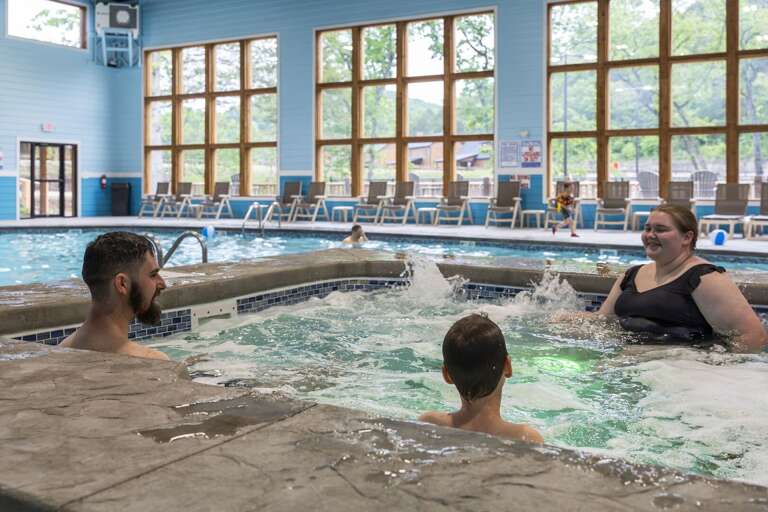 Family Frolicking In Indoor Pool, Framed By Windows