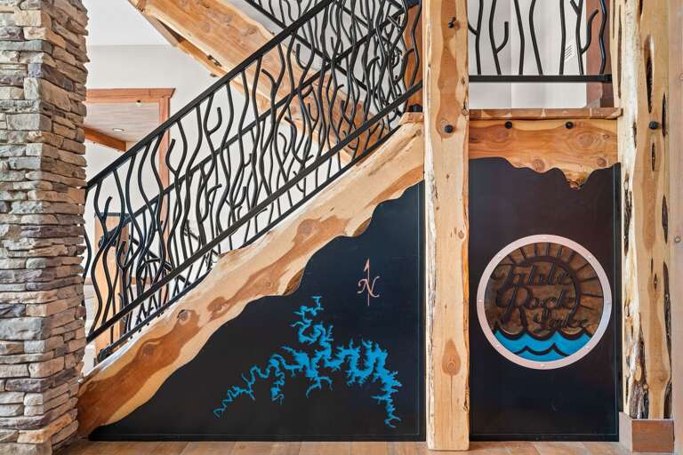 Wooden Stairs With Wavy Wrought-iron Railing Beside Stone Column And Painted Door