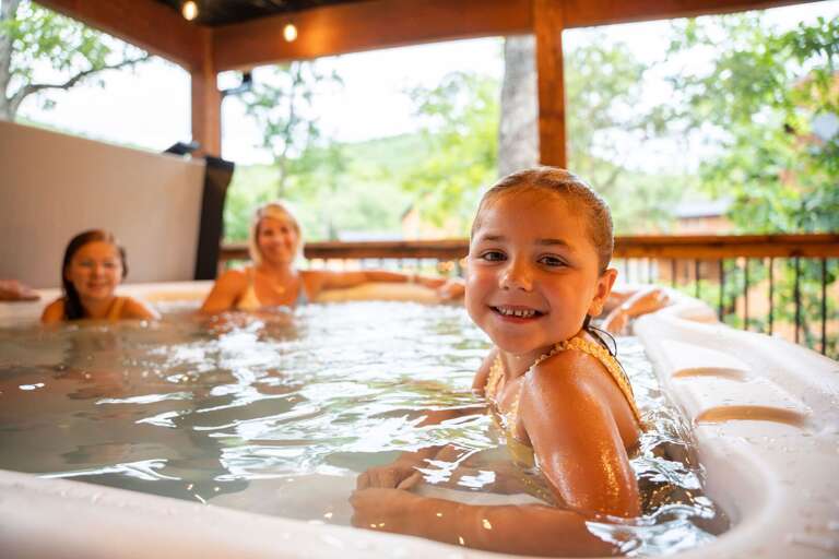 Family Enjoying Vacation Rental Hot Tub Under Wooded Canopy
