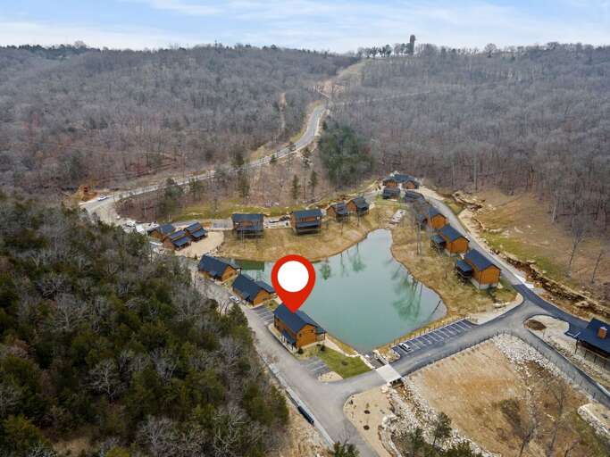 Aerial View Of Cabins Clustered Around A Lake, Nestled In A Hilly Landscape