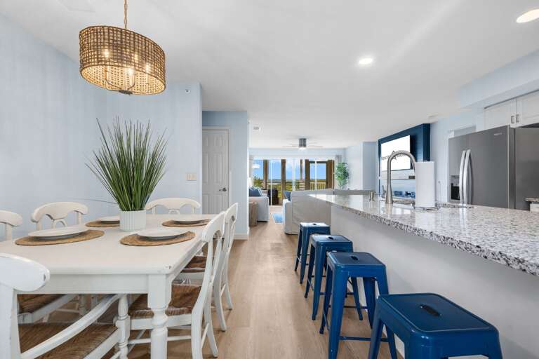 Bright Blue Bar Stools Balance Beside A Breezy White Dining Area With Pristine Kitchen Backdrop