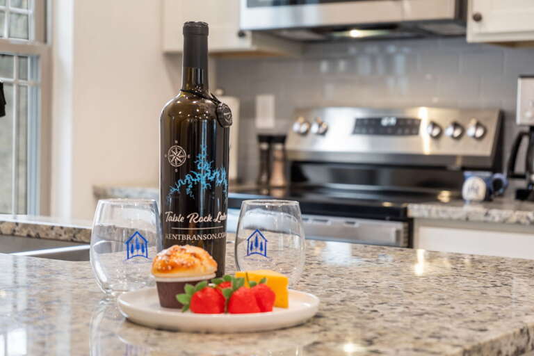 Kitchen Counter With Wine Bottle, Glasses, And Fruit Plate In A Vacation Rental