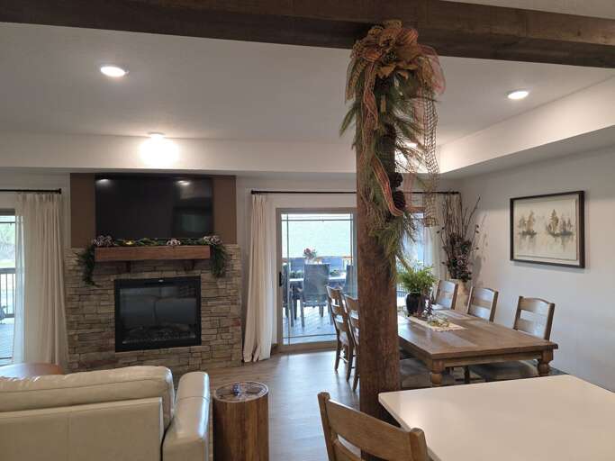 Spacious Living Room With Stone Fireplace, Dining Area, And Balcony Access