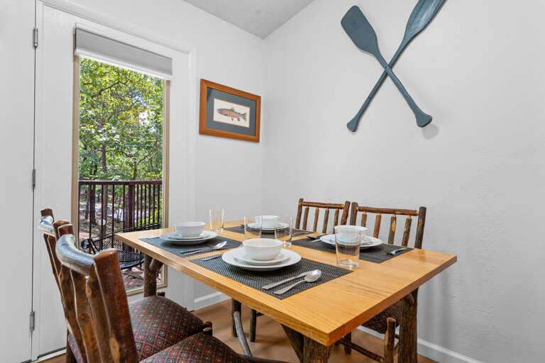 Dining Room With Wooden Table Set For Four, Paddles On Wall, Balcony Door Open