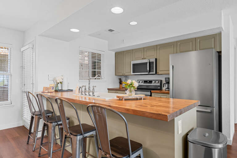 Bright, Breezy Kitchen Space With Bar Stools And Butcher Block Counter