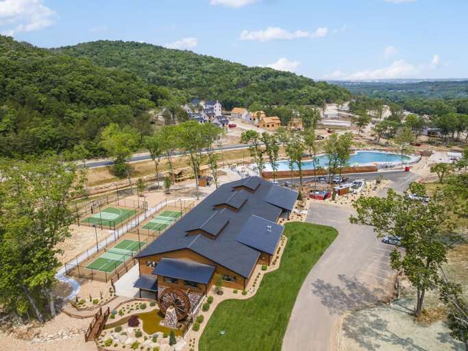 Aerial View Of A Vacation Rental Property Near A Pool And Sports Courts, Nestled In Nature