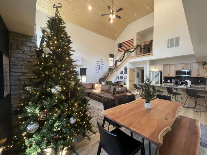 Spacious Living Space With Christmas Tree, Staircase, And Kitchen Area