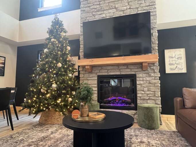 Living Room With Festive Tree By Fireplace Flanked By Furniture