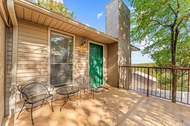 Vacation Rental Balcony With Verdant Vista, Vibrant Green Door, And Seating Set