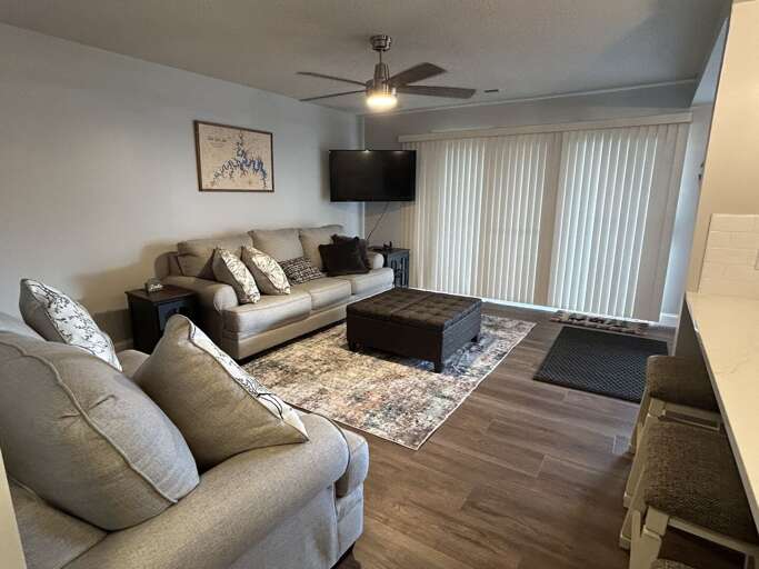 Living Room With Sofas, Sliding Door Blinds, And Mounted TV