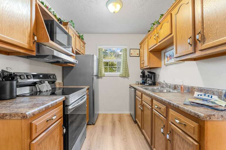 Compact Kitchen With Wooden Cabinets, Stainless Steel Appliances, And A Small Window