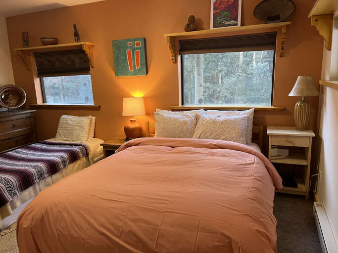 Wake up to peaceful forest views through large windows in your cozy bedroom, where warm lighting and comfortable beds invite you to relax and recharge after mountain adventures.
