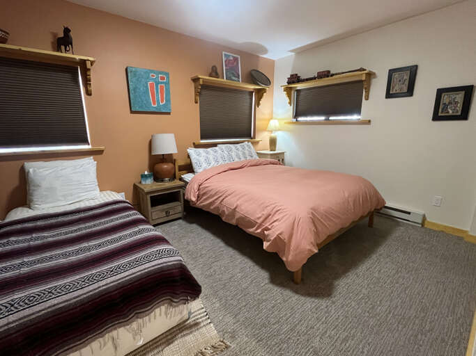 Your cozy bedroom features two comfortable beds dressed in soft linens, warm wood accents, and thoughtful décor—perfect for restful nights in a welcoming Southwestern-inspired setting.