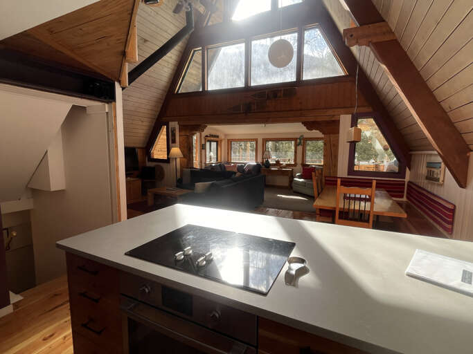 Sunlight streams through vaulted windows, illuminating your open-plan retreat where warm wood tones and a modern kitchen invite cozy mountain getaways.