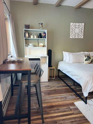 Relax in your stylish studio with crisp white linens, exposed beams, and a compact kitchenette for morning coffee.