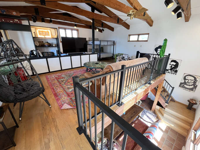Cozy loft with exposed beams and bunk beds overlooks the inviting living area below through stylish railings.