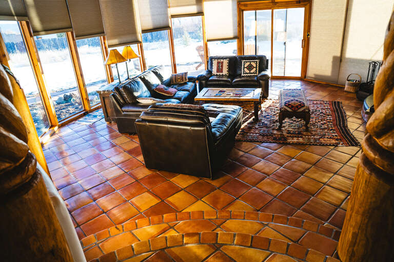 Sink into leather sofas by floor-to-ceiling windows showcasing snowy mountain views in your cozy living room retreat.