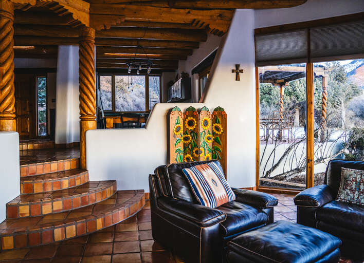 Sink into buttery leather chairs by your adobe fireplace, where hand-carved beams frame stunning mountain vistas through floor-to-ceiling windows.