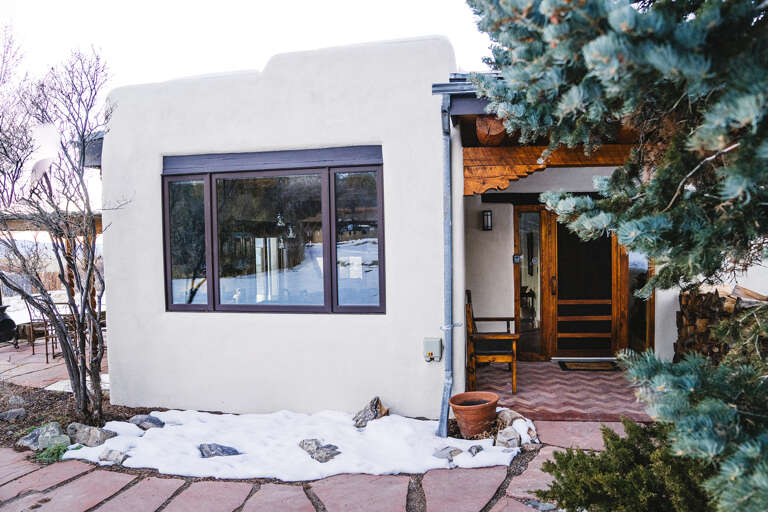 Modern adobe-style retreat with warm wood accents nestled among evergreens, offering a peaceful winter getaway with contemporary comfort.