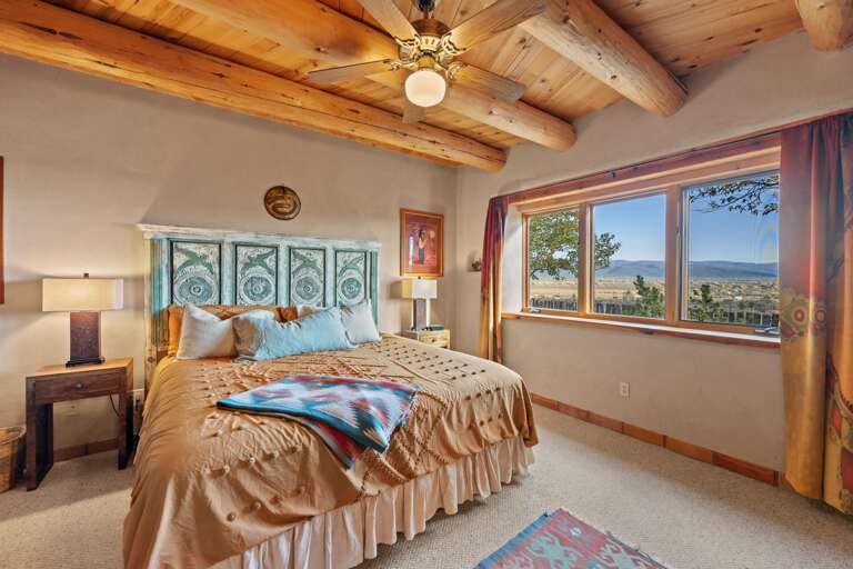 King bedroom with cozy bed, wall to wall carpet and picture windows