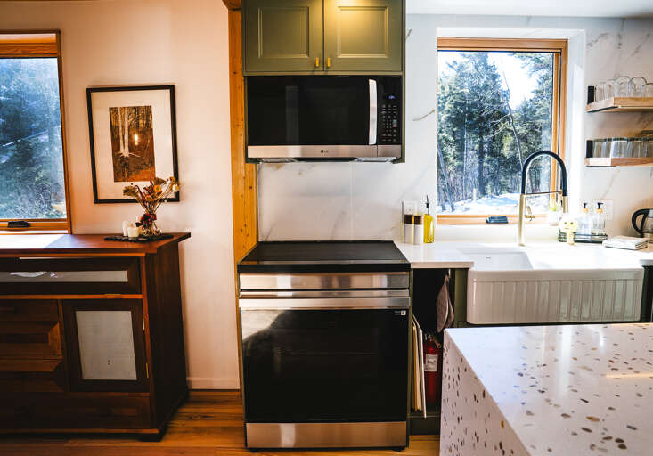 A fully equipped kitchen features modern appliances and forest views