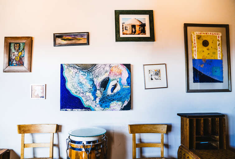Cozy up in your artistic haven where colorful paintings and warm wooden furniture create the perfect creative retreat atmosphere.