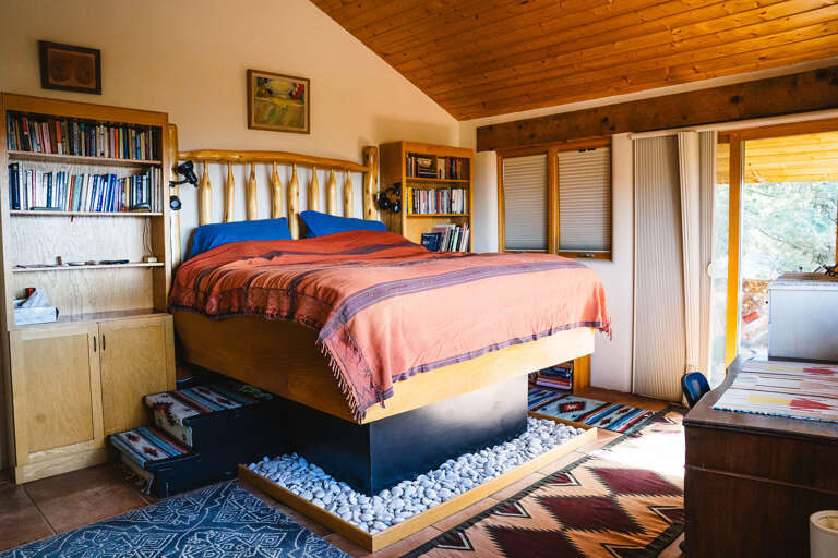 Drift off in this unique bedroom featuring a floating bed over smooth river rocks, surrounded by cozy wood beams and your own library nook.