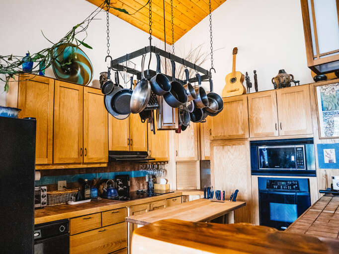 Your fully equipped kitchen features warm wood cabinets, modern appliances, and a charming pot rackâperfect for preparing meals together.