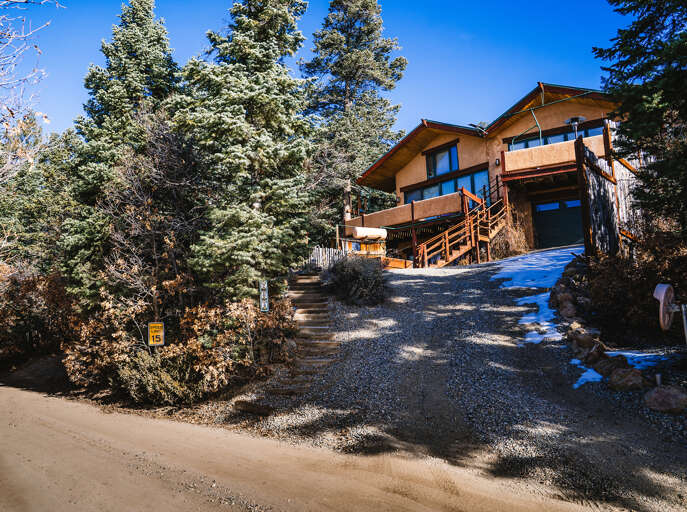 Modern mountain retreat nestled among snow-dusted evergreens with multi-level decks and natural wood architecture creating a perfect winter escape.