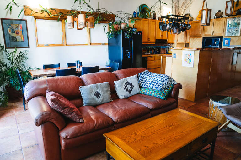 Sink into the plush leather sofa surrounded by trailing plants and warm wood tones in your open-concept retreat.