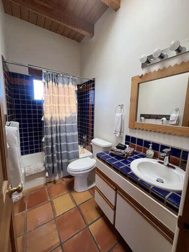 Refresh in your charming bathroom featuring vibrant blue tiles, rustic terracotta floors, and exposed wooden beams that create authentic character.