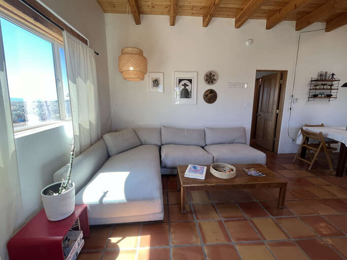 Relax in your bright, airy living room with natural wood beams and comfortable seating where morning light streams through windows.