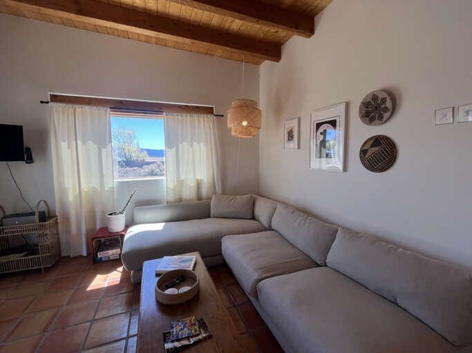 Relax on your plush sectional sofa under rustic wooden beams while enjoying mountain views through bright windows.