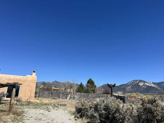 Adobe-style property nestled beneath dramatic mountain peaks under endless blue skies in a high desert landscape.